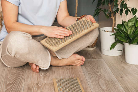 A woman sits on the floor with a wooden sadhu board with nails. Practice standing on nails. Indian Practicesの写真素材