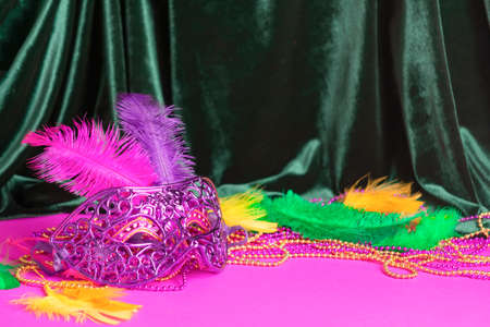 Festive carnival mask for Mardi Gras festival, green velvet curtain purple background. Masqueradeの写真素材