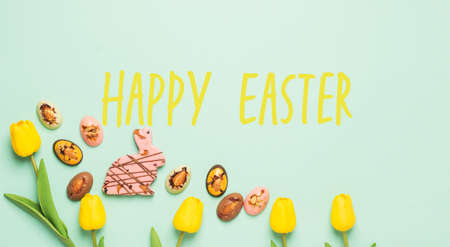 Easter composition with spring flowers tulips Easter chocolate eggs and rabbit, pastel backgroundの写真素材