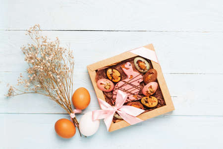 Easter composition box of chocolate eggs Easter bunny eggs natural colors wooden pastel backgroundの写真素材