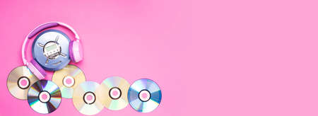 Personal compact portable CD player disks purple headphones on a pink background.