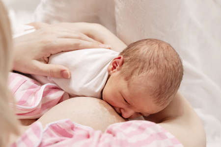 A mother is breastfeeding her little baby. Newborn, breastfeeding. Top view selective soft focus