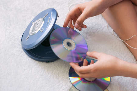 Girl connects headphones to CD player to listen to music. Recreation entertainment leisure teenager