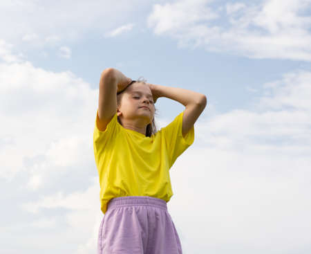 Girls blonde wearing yellow T-shirt on blue sky background, psychological adolescent problemsの写真素材