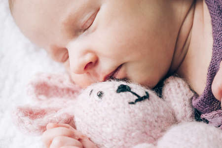 Cute newborn baby girl sleeps with her favorite toy, the first month of life. Close-up soft focusの写真素材