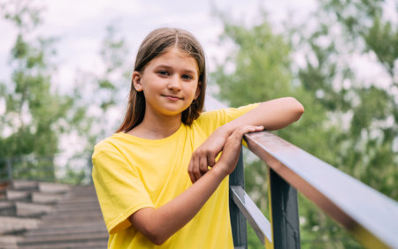 Portrait of a blonde girl in a bright yellow T-shirt against the background of the parkの写真素材