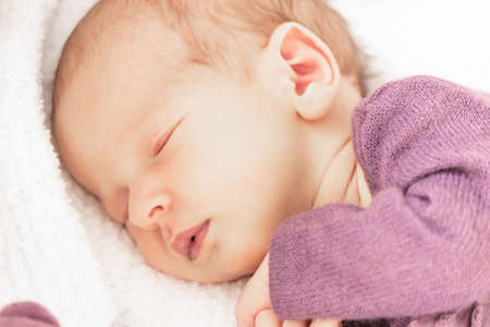 Cute newborn baby girl sleeps at home in her crib with her favorite toy, the first month of lifeの写真素材
