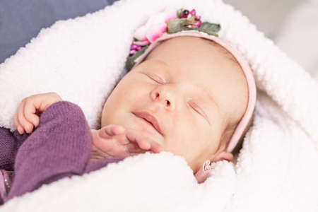 Sleeping newborn baby girl on a white fluffy soft blanket. First monthの写真素材