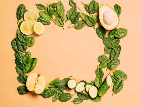 Green fresh fruits and vegetables, spinach, apple, lime, avocado, cucumber light brown background