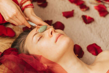 A woman makes a gouache massage with a jade roller. Mental health care, meditation and relaxationの写真素材