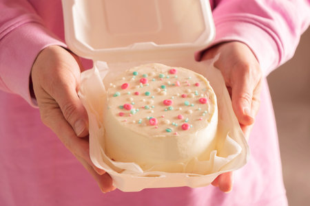 Woman is holding bento cake in her hands. Korean style cakes in box for one personの写真素材