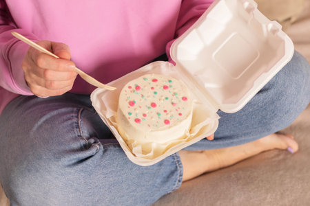 Woman is holding bento cake in her hands. Korean style cakes in box for one personの写真素材