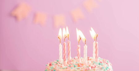 Festive cake with candles on the background of a festive pink wall with flags. Holiday conceptの写真素材