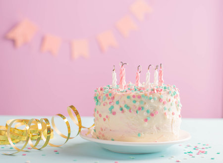 Festive cake with extinguished candles against background of festive pink wall flags in serpentineの写真素材