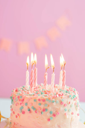 Festive cake with candles on the background of a festive pink wall with flags. Holiday conceptの写真素材