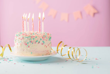 Festive cake with candles on the background of festive pink wall with gifts and flags in serpentineの写真素材