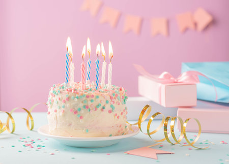 Festive cake with candles on the background of festive pink wall with gifts and flags in serpentineの写真素材