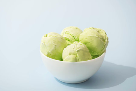 Homemade ice cream flavored with green matcha, lime or pistachio, in white bowls on a white kitchen table, copy spaceの写真素材