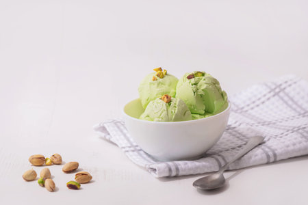 Pistachio homemade Ice cream in a white bowl on a white kitchen table, copy space. Summer cooling dessertsの写真素材