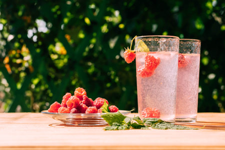 Drink from ripe red raspberries in two transparent glasses, summer background. Summer seasonal freshly refreshing drinkの写真素材
