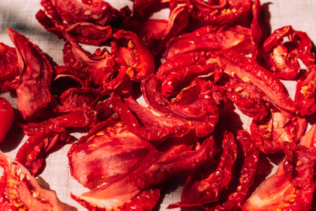 Appetizing sun-dried tomatoes lie on the kitchen table, bright sunlight and shadow, top view. Harvesting and processing vegetables, organic foodの写真素材