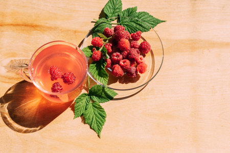 Ripe red raspberry drink in a transparent glass wooden background, summer seasonal food and refreshing drinksの写真素材