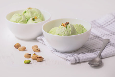 Pistachio homemade Ice cream in a white bowl on a white kitchen table, copy space. Summer cooling dessertsの写真素材