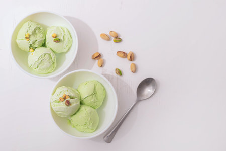 Pistachio homemade ice cream decorated with nuts in white bowls on a white kitchen table, copy space. Summer cooling dessertsの写真素材