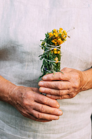 Womens hands hold a bundle of medicinal herbs. Woman herbalist doctor prepares herbal collection, incenseの写真素材