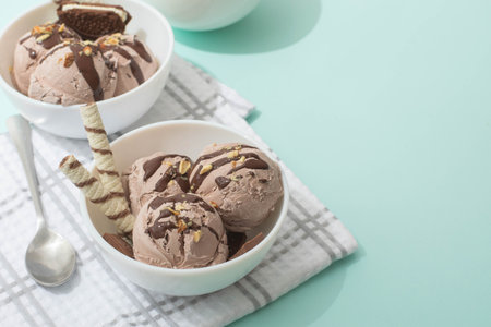 Chocolate ice cream decorated with nuts and chocolate icing, in a white bowl, blue background. Summer homemade cooling dessertsの写真素材