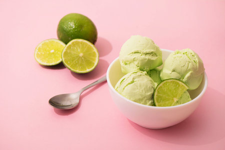 Ice cream with lime flavor and slices of fresh lime in a white bowl, pink background, copy space. Summer cooling desserts,の写真素材