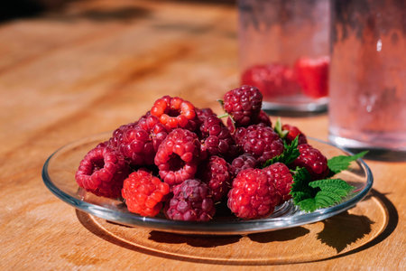Red raspberry in a plate on the kitchen table, summer food. Background of fruity ripe berriesの写真素材
