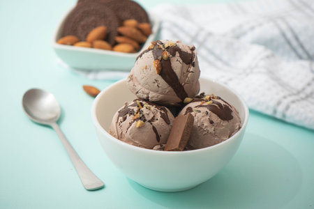 Chocolate ice cream decorated with nuts and chocolate icing, in a white bowl, blue background. Summer homemade cooling dessertsの写真素材