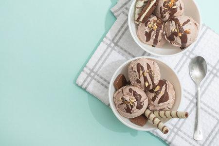 Chocolate homemade ice cream decorated with nuts, chocolate chips, wafer rolls, in white bowl. Summer cooling dessertsの写真素材