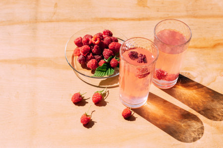 Ripe red raspberry drink in a transparent glass wooden background, summer seasonal food and refreshing drinksの写真素材