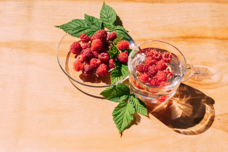 Ripe red raspberry drink in a transparent glass wooden background, summer seasonal food and refreshing drinksの写真素材
