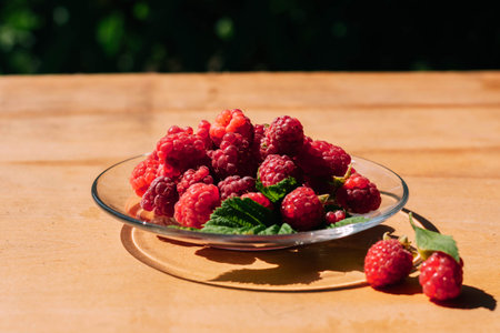 Red raspberry in a plate on the kitchen table, summer food. Background of fruity ripe berriesの写真素材
