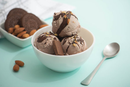 Chocolate ice cream decorated with nuts and chocolate icing, in a white bowl, blue background. Summer homemade cooling dessertsの写真素材