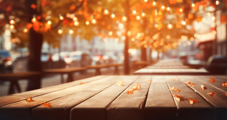 Empty wooden table top against the backdrop of an autumn cityscape, city street with orange foliage garlands of lightsの素材