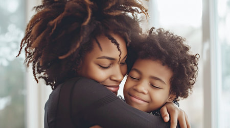 Black mother hugs her son tightly, their faces touching tenderly, sharing a sweet moment of connection, family relationshipsの素材