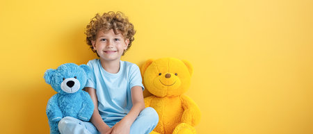 A child with a smile holds yellow and blue teddy bears. Minimalistic yellow background, copy spaceの素材
