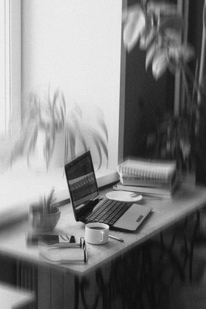 Black and white workspace with laptop and office supplies on wooden deskの写真素材