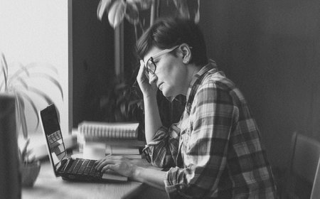 Elderly caucasian female working on laptop in black and white sceneの写真素材