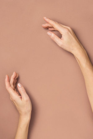Female hands gracefully lying gesturing on beige background. Mockup, copy space