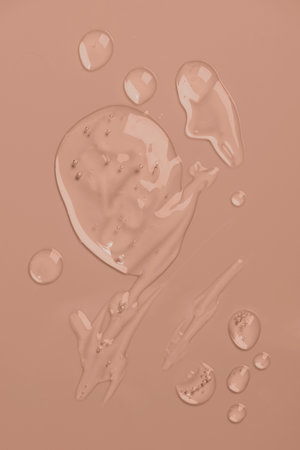Transparent textured drops of gel-like liquid with bubbles on pastel beige backgroundの写真素材
