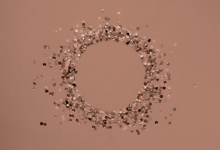 Circular arrangement of shimmery sequins on a soft pink background