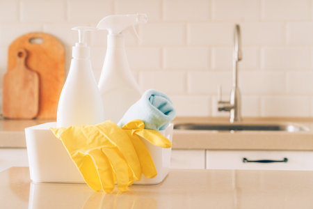 Cleaning supplies in kitchen with yellow gloves and spray bottle on counterの写真素材