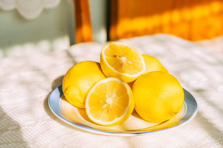 Fresh lemons on sunlit plate displaying vibrant yellow tonesの写真素材