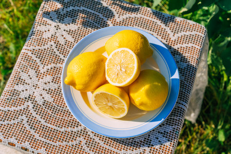 Fresh lemons on lace-covered table in sunny garden settingの写真素材
