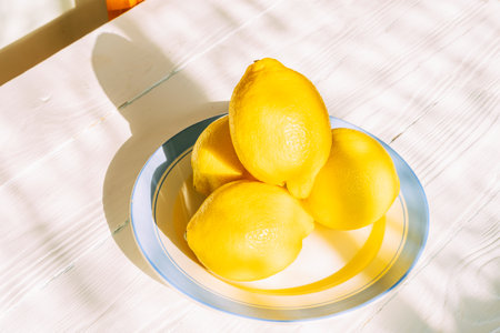 Fresh lemons on a sunlit plate in bright kitchen settingの写真素材